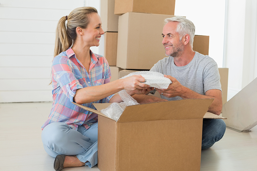 Happy couple unpacking cardboard moving boxes 